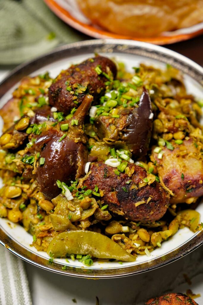 Close-up of Undhiyu showing purple yam, papdi, sweet potato, baby eggplants, and golden-brown methi muthia