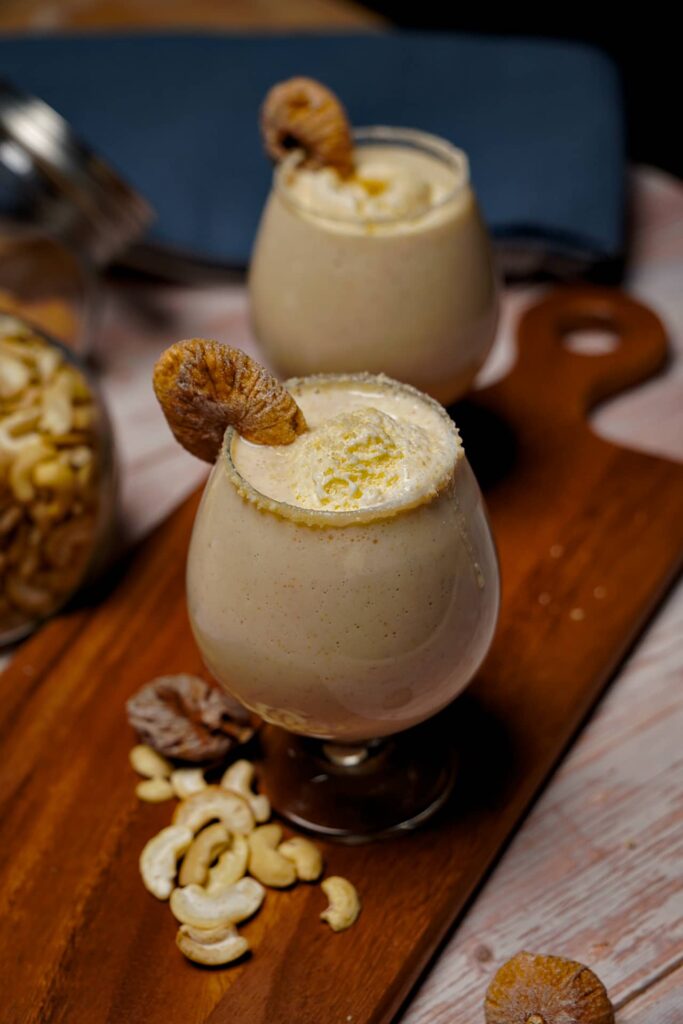 Kaju Anjeer Milkshake topped with a scoop of vanilla ice cream, served in a glass.