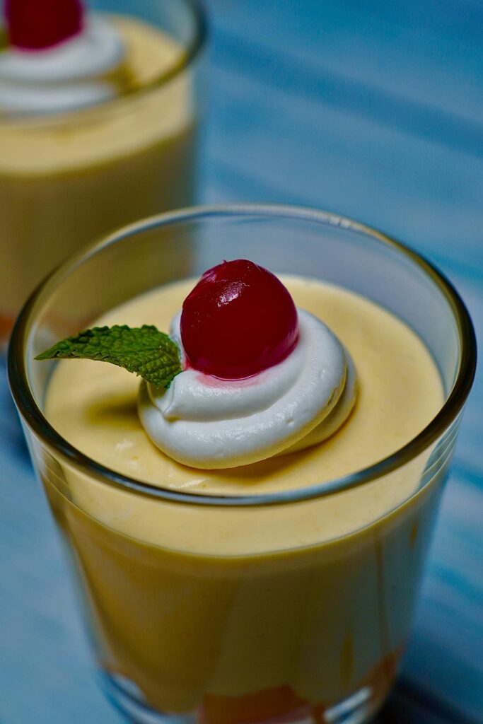 Heavenly Mango Mousse garnished with maraschino cherries and fresh mint leaves for an elegant presentation.